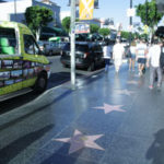 Straße mit Sternen (walk of fame) rechts Straße mit Sternen (walk of fame) rechts sind einige Leute, links ein buntes Auto