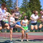Jugendliche Tennisspieler springen freudig in die Luft.
